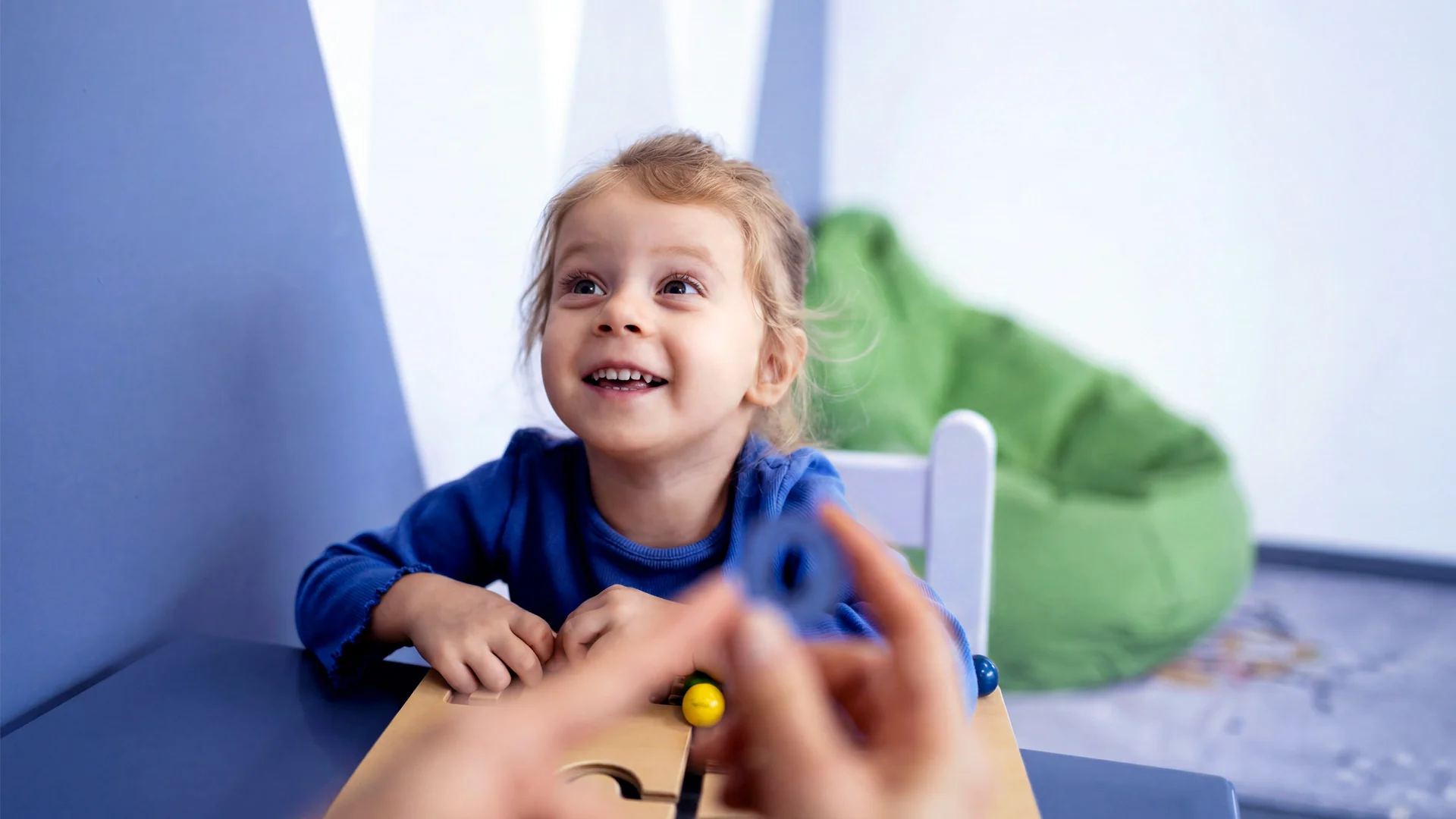 Child smiling with toy at a table