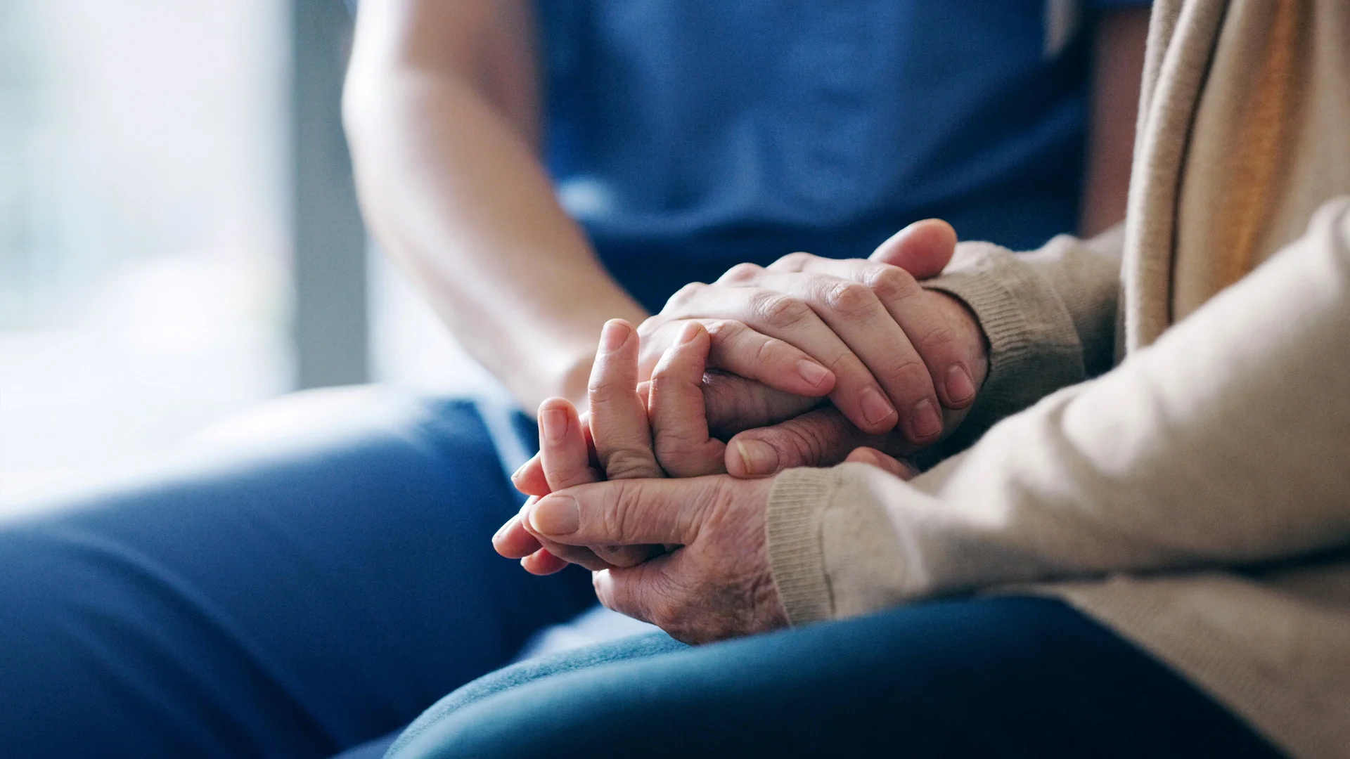 Two pairs of hands holding one another