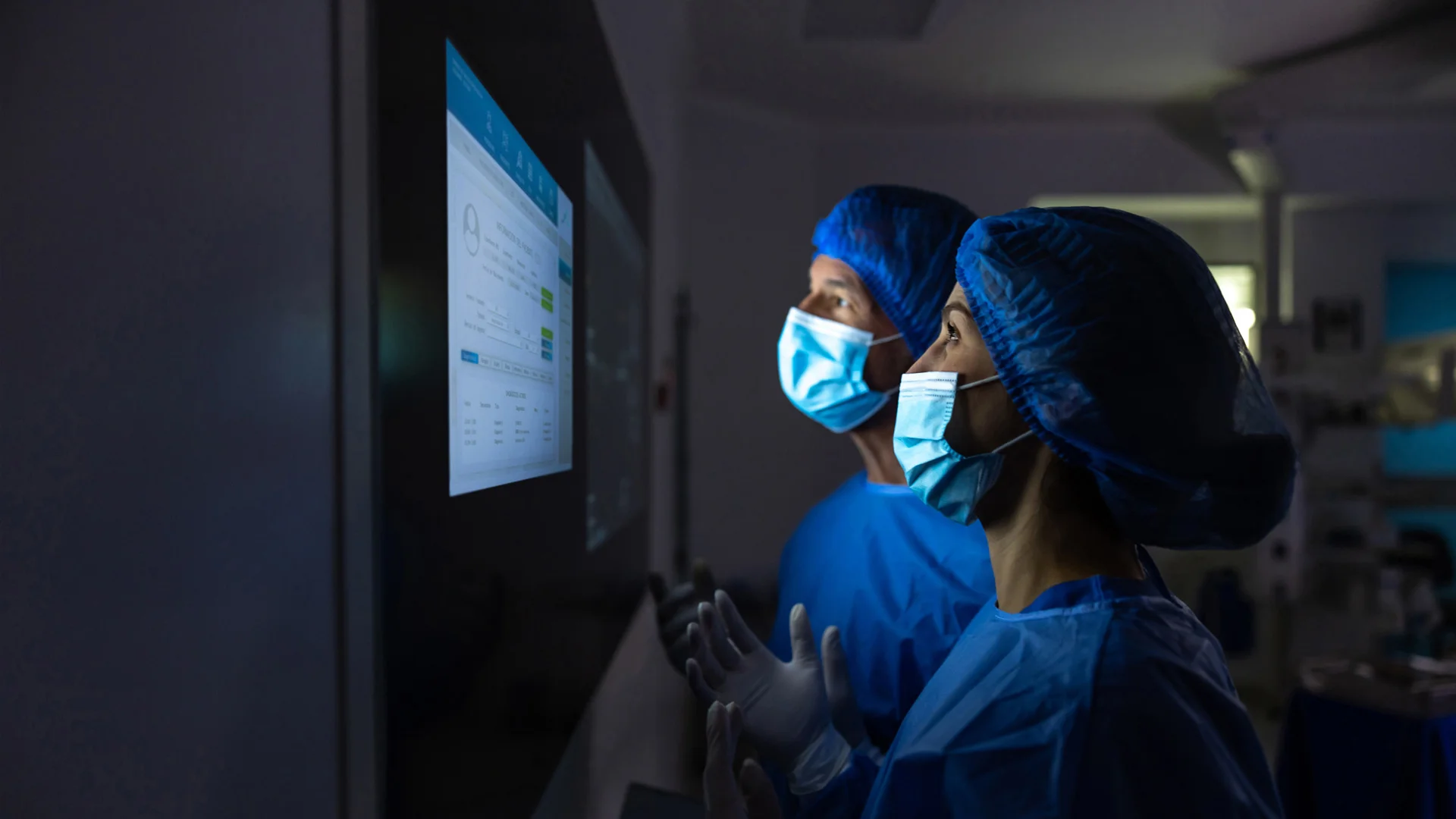 Two surgeons in masks and scrubs looking at screen