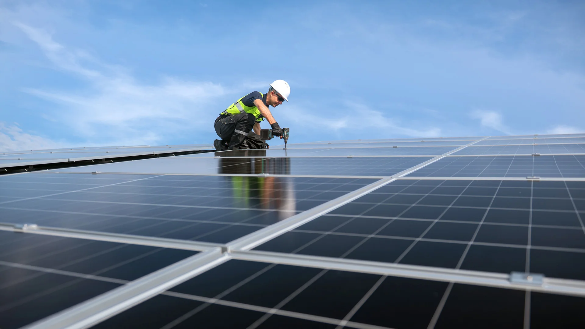 Man in hight vis and hard hat drilling solar panels