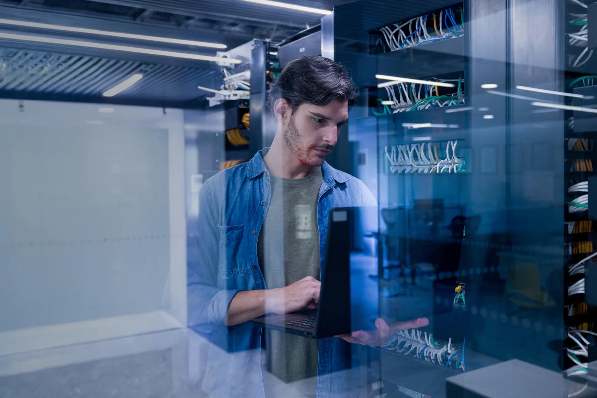 Man working on laptop in a room full of wires